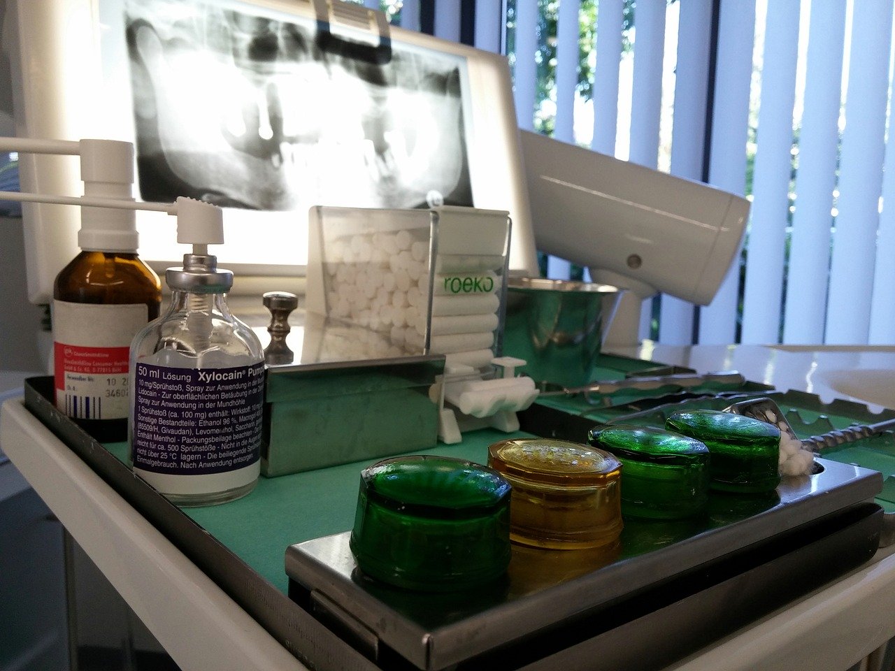 Dentist table filled with equipment, including an x-ray picture and cotton swabs