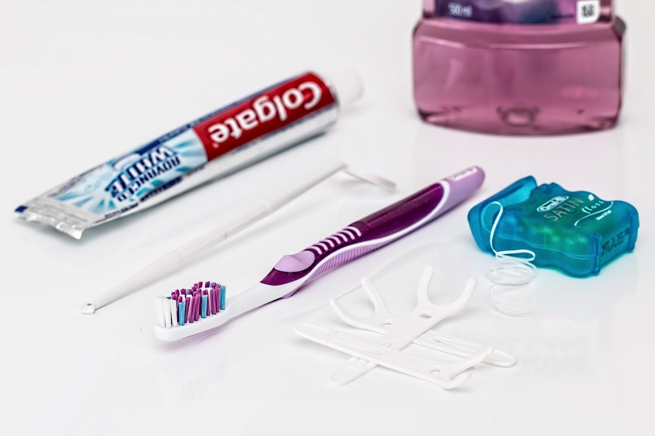 Toothpaste, mirror, toothbrush, floss, and mouthwash sit on a table.