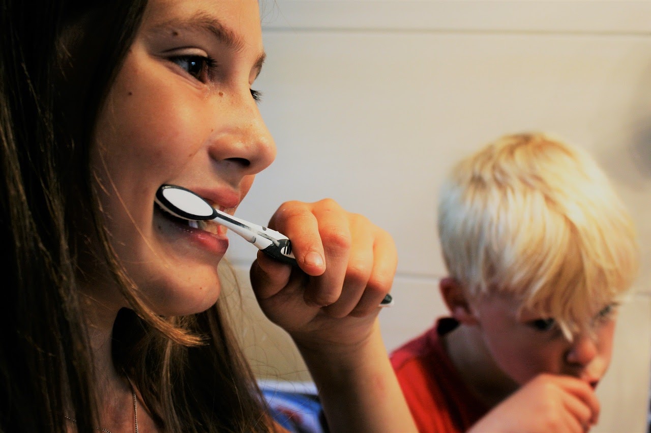 A woman and her son brush their teeth correctly after talking to their dentist.