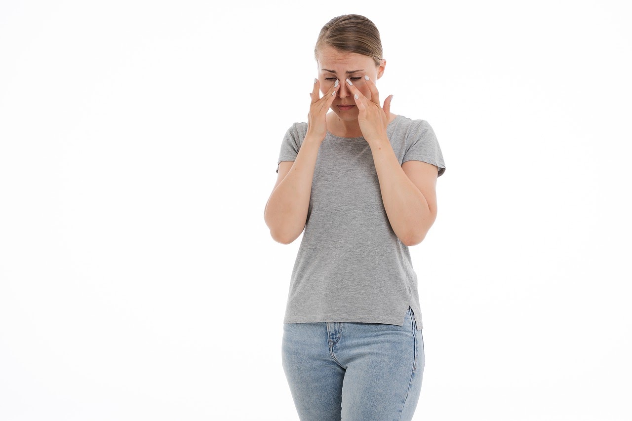A woman touching her nose where she is experiencing facial pain.