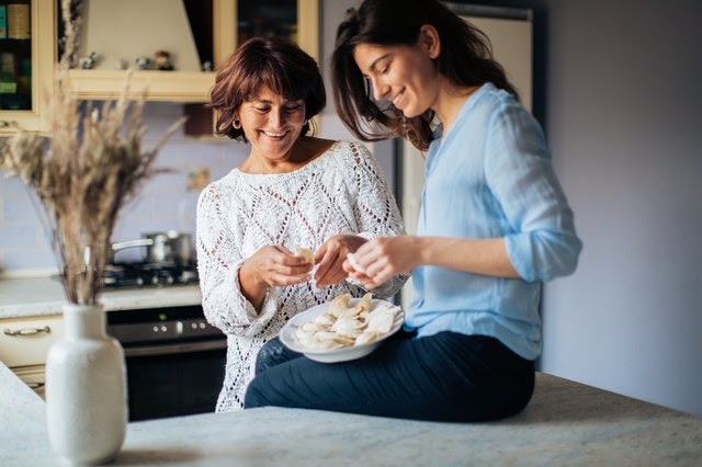 Two happy women bake healthy holiday treats together.