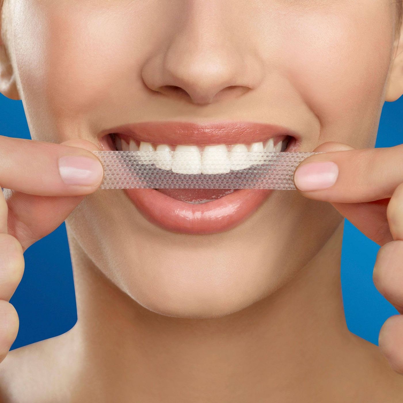 someone applies a Crest Whitening Strip to their teeth as a safe tooth whitening option