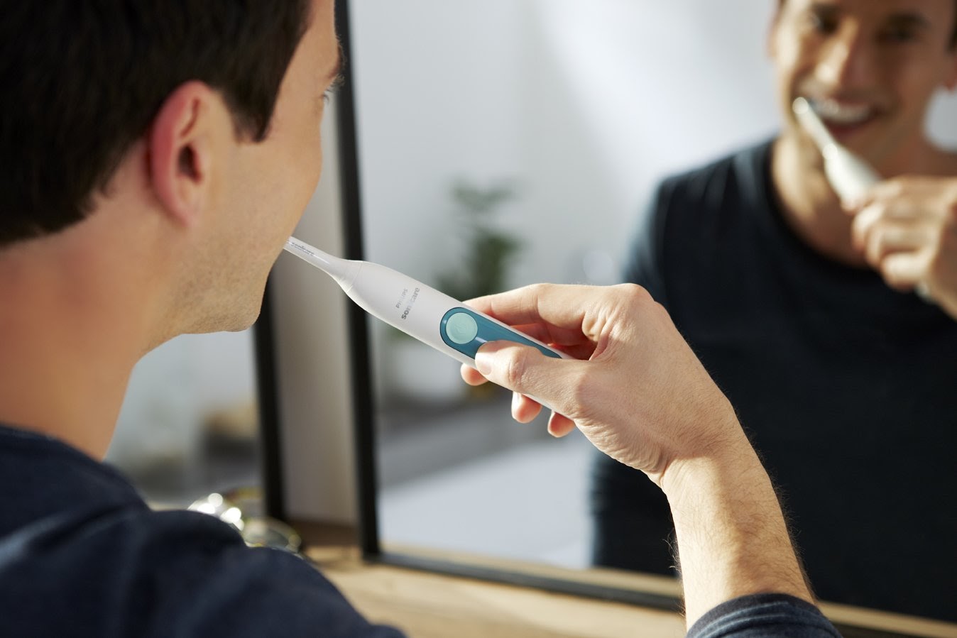 man brushes his teeth with a family dentist recommended electric toothbrush