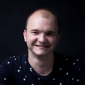 Portrait Bild vom Team Mitglied Dennis, in dem er lächelnd in die Kamera sieht.