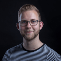 Portrait Bild vom Team Mitglied Lucas, in dem er lächelnd in die Kamera sieht.