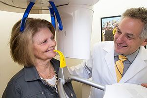 Dr. Burden smiles at female patient standing in cone beam scanner