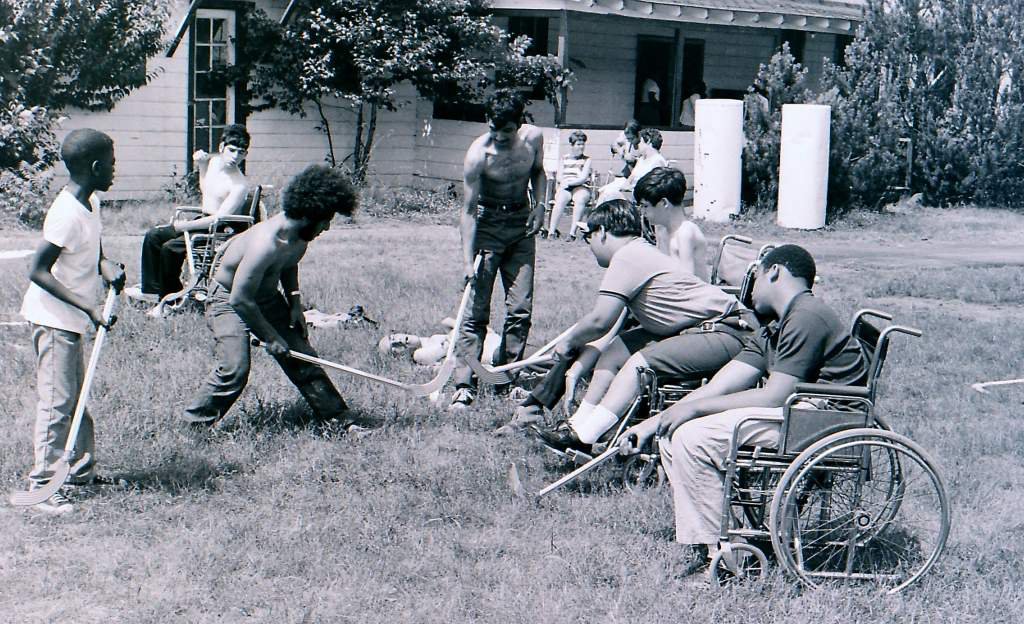 Diversidad en estado puro. Adultos y adolescentes, con y sin discapacidad, negras y blancas, jugando al hockey sobre la hierba del campamento. Un ejemplo de inclusión y toda una declaración de intenciones en plena decada de los 70.