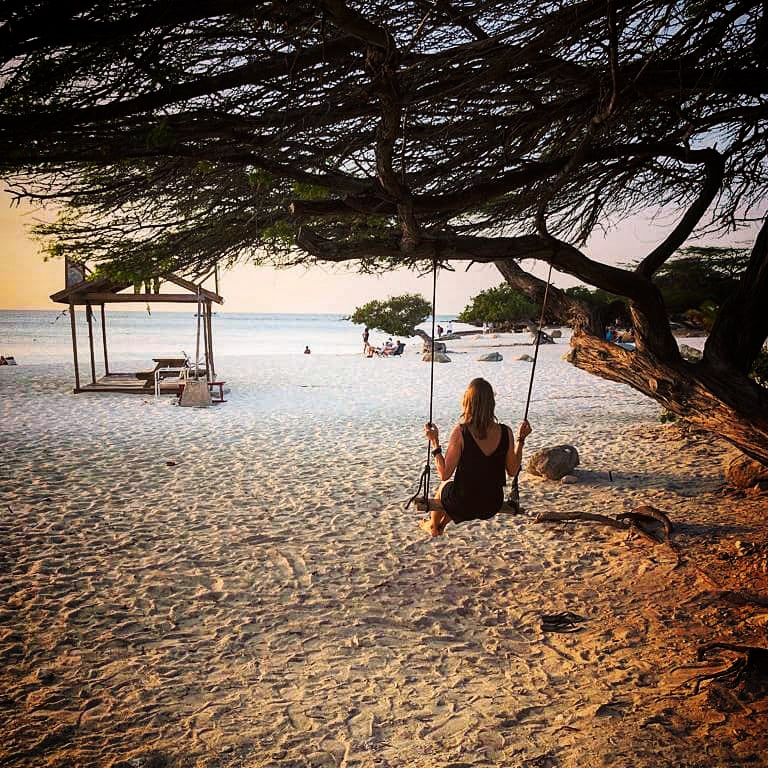 Woman on a swing on the beach watching the sunset in Aruba