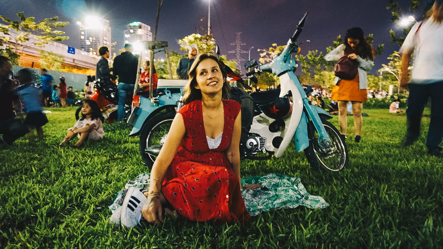 girl sitting with blue honda cub in the park at night