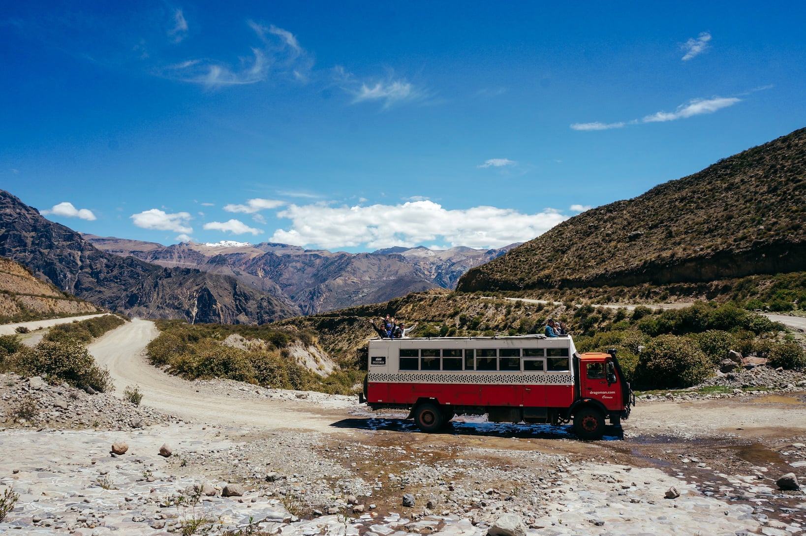Overland red and white Dragoman Tour bus parked at Colca Canyon, Peru.