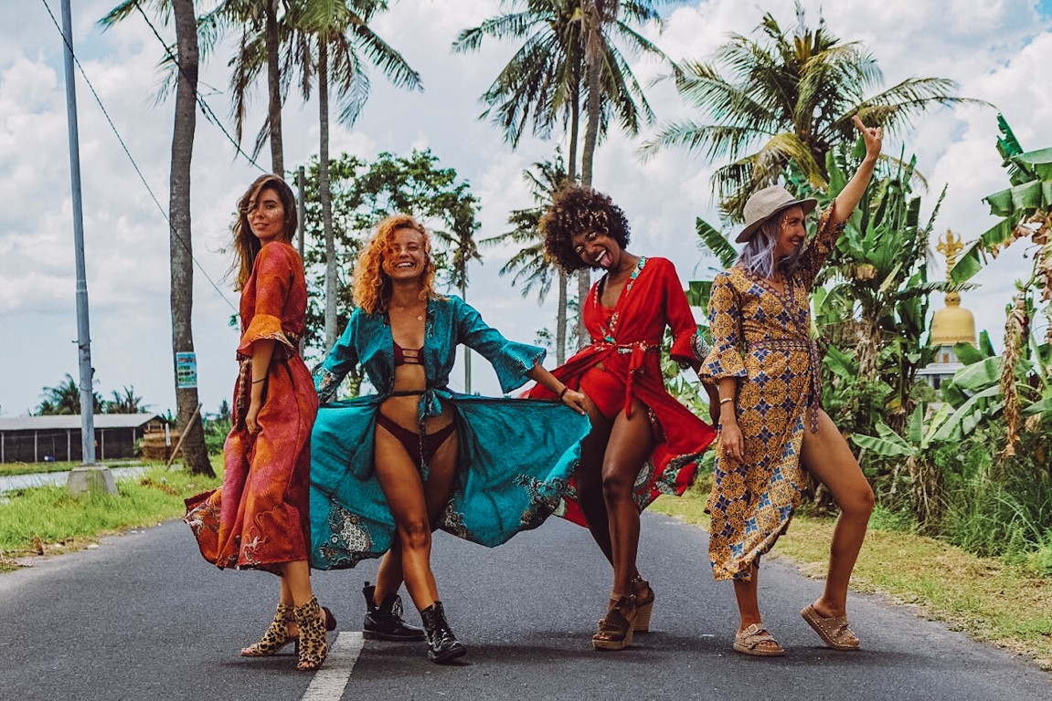 A group of women in colorful dresses happily posing in the middle of the street in Bali