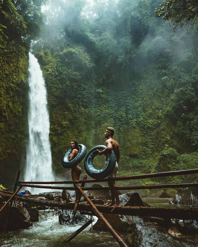 couple exploring waterfall in lush green jungle