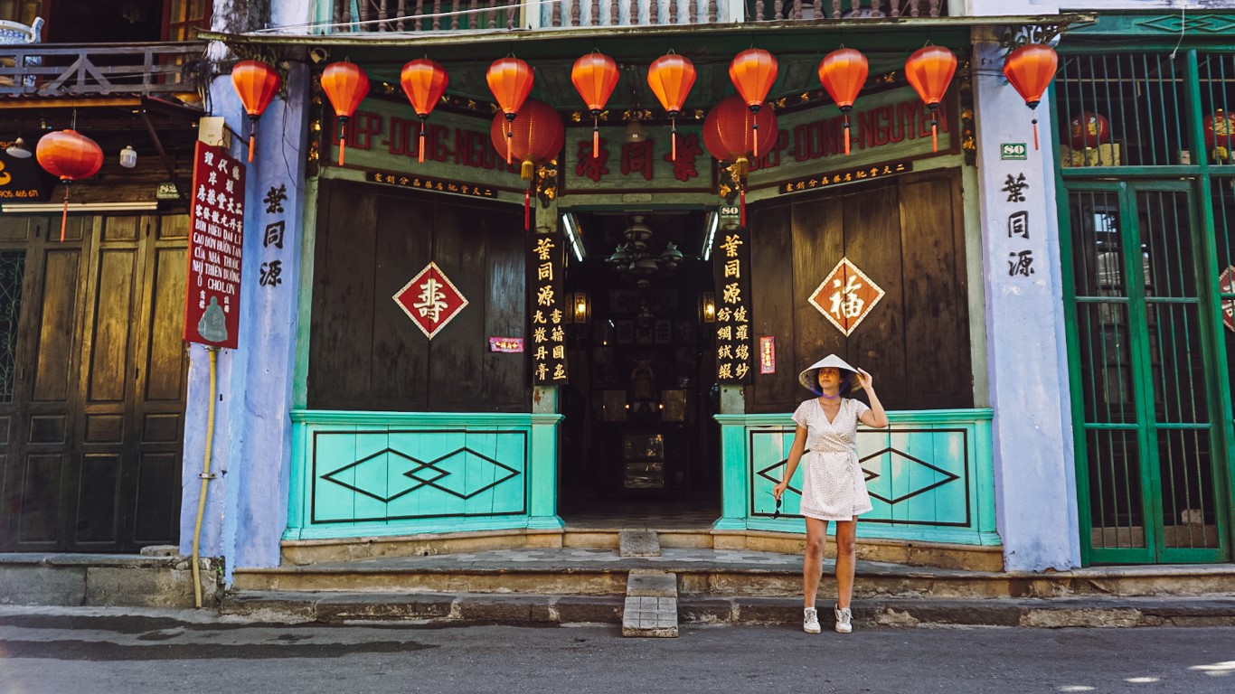 a woman posing in front of a chinese medicine shop in hoi an, vietnam
