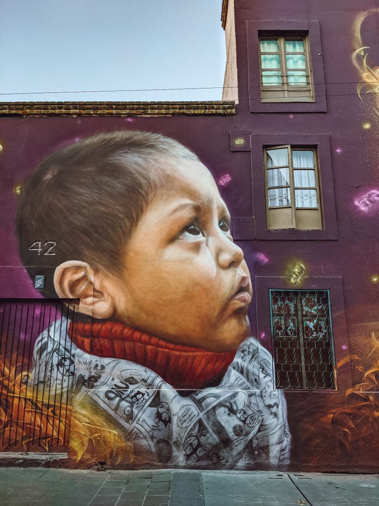 a giant mural on a building in mexico city depicting the side of boy looking up towards the sky