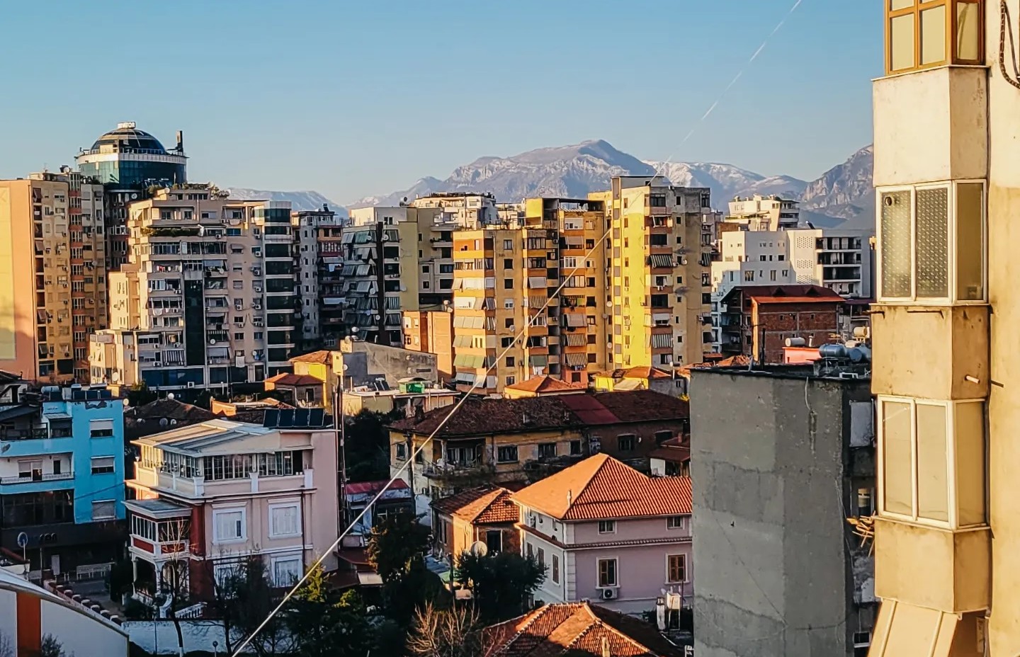 a few of a city center from a window with the golden light of sunset and snow covered mountains in the distance