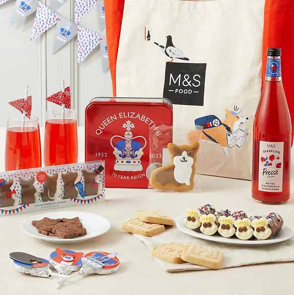 A selection of jubilee inspired foods from Marks and Spencer. Corgi themed cakes, a strawberry and eldeflower soft drink and a jubilee themed tote bag.