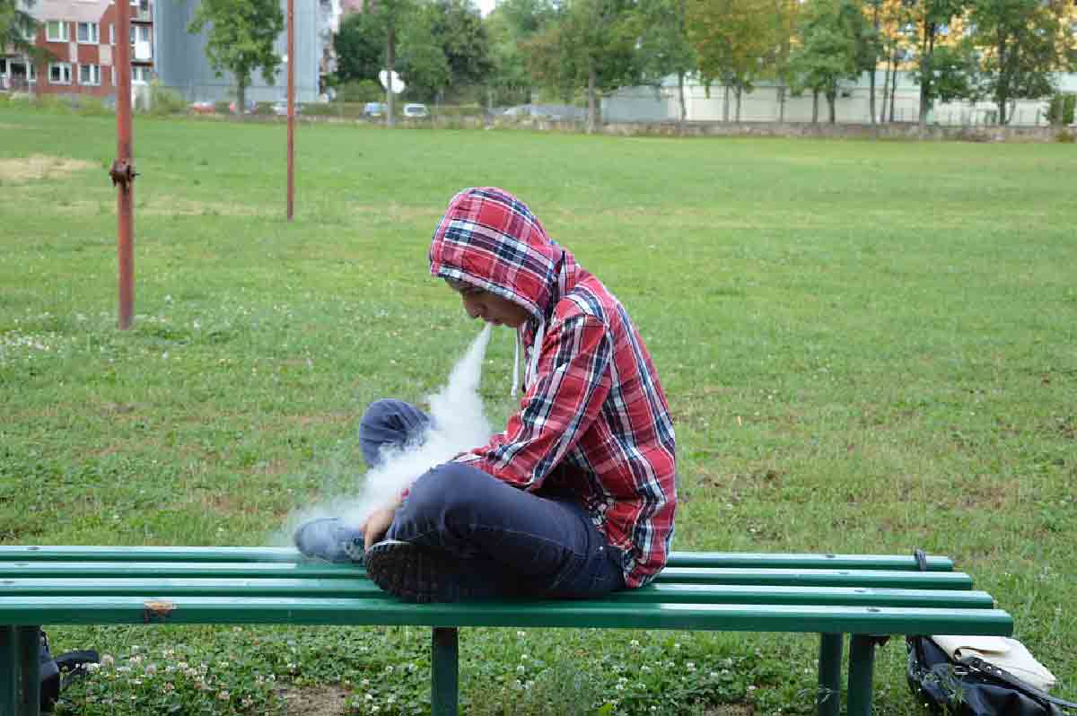 un ragazzo viene ripreso mentre svapa su una panchina
