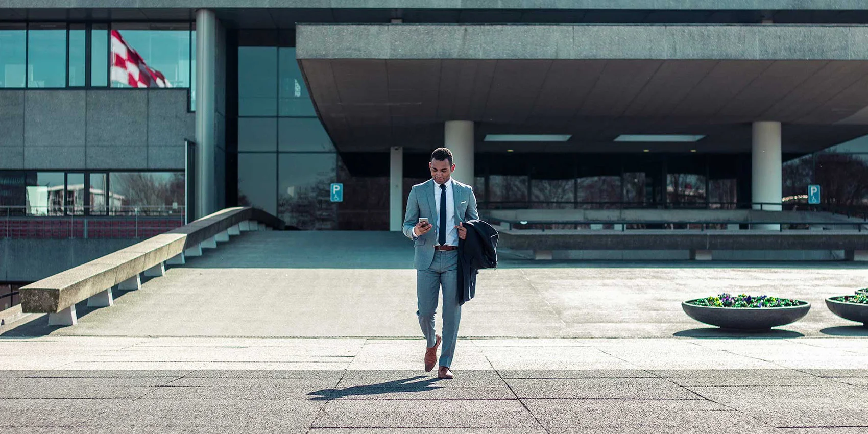 Man with formal attire crossing the road while texting