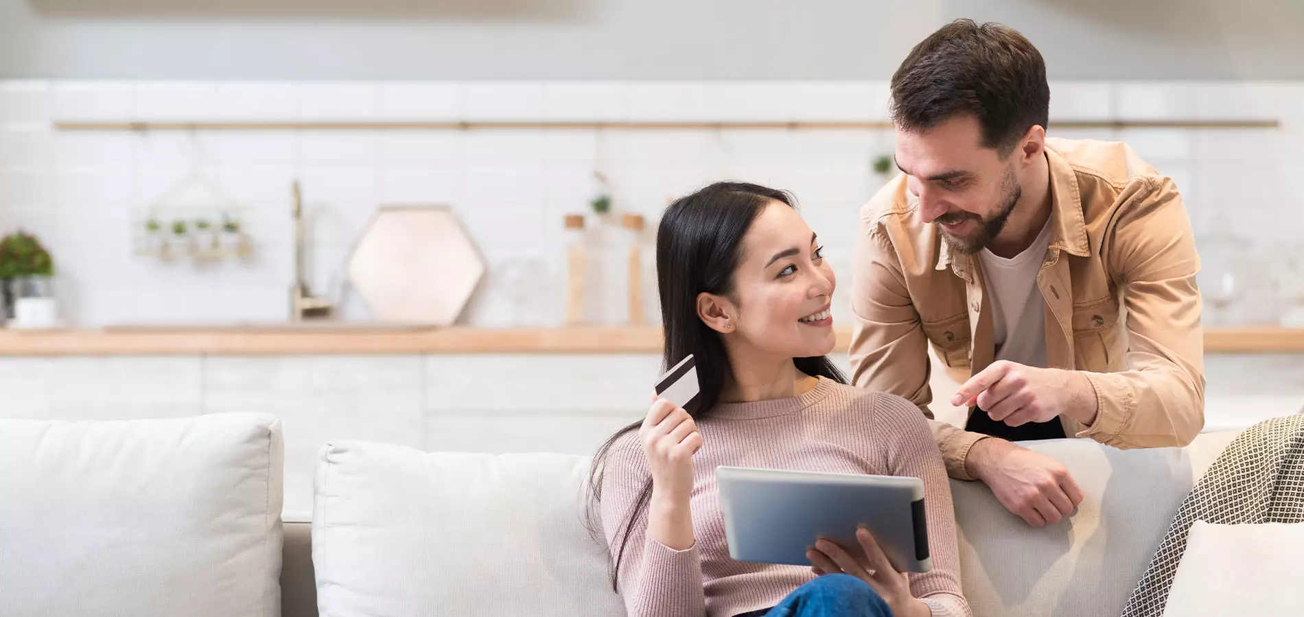 Happy woman smiling while holding a credit card and an iPad