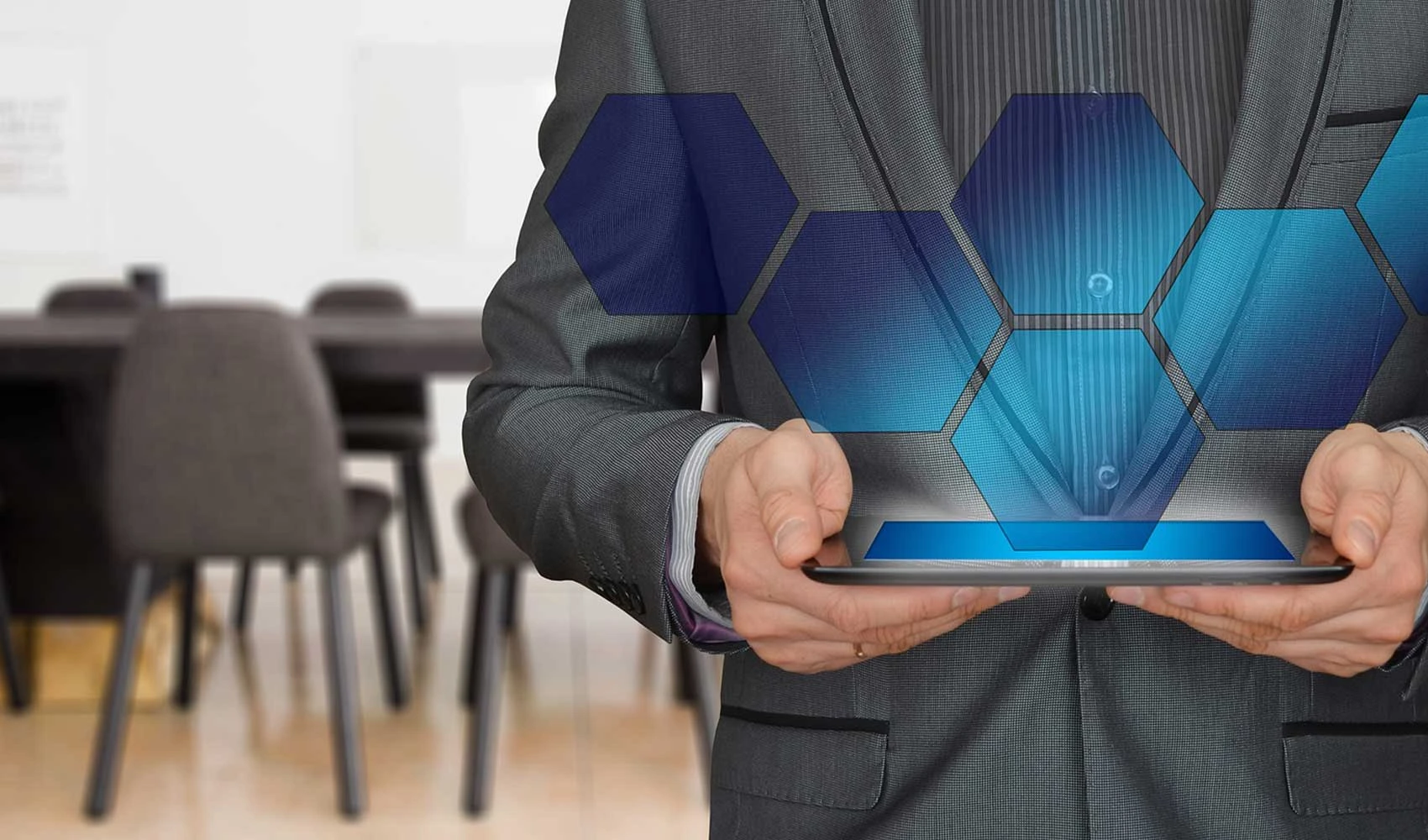 Cropped photo of a business man holding an iPad showing a hexagon hologram