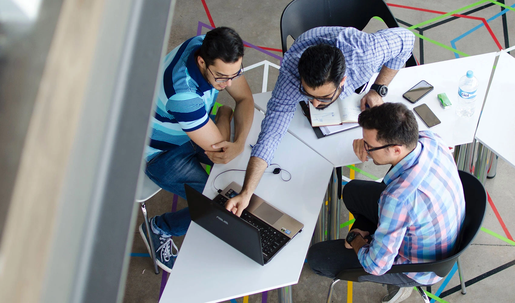 Top view photo of 3 men in front of laptop