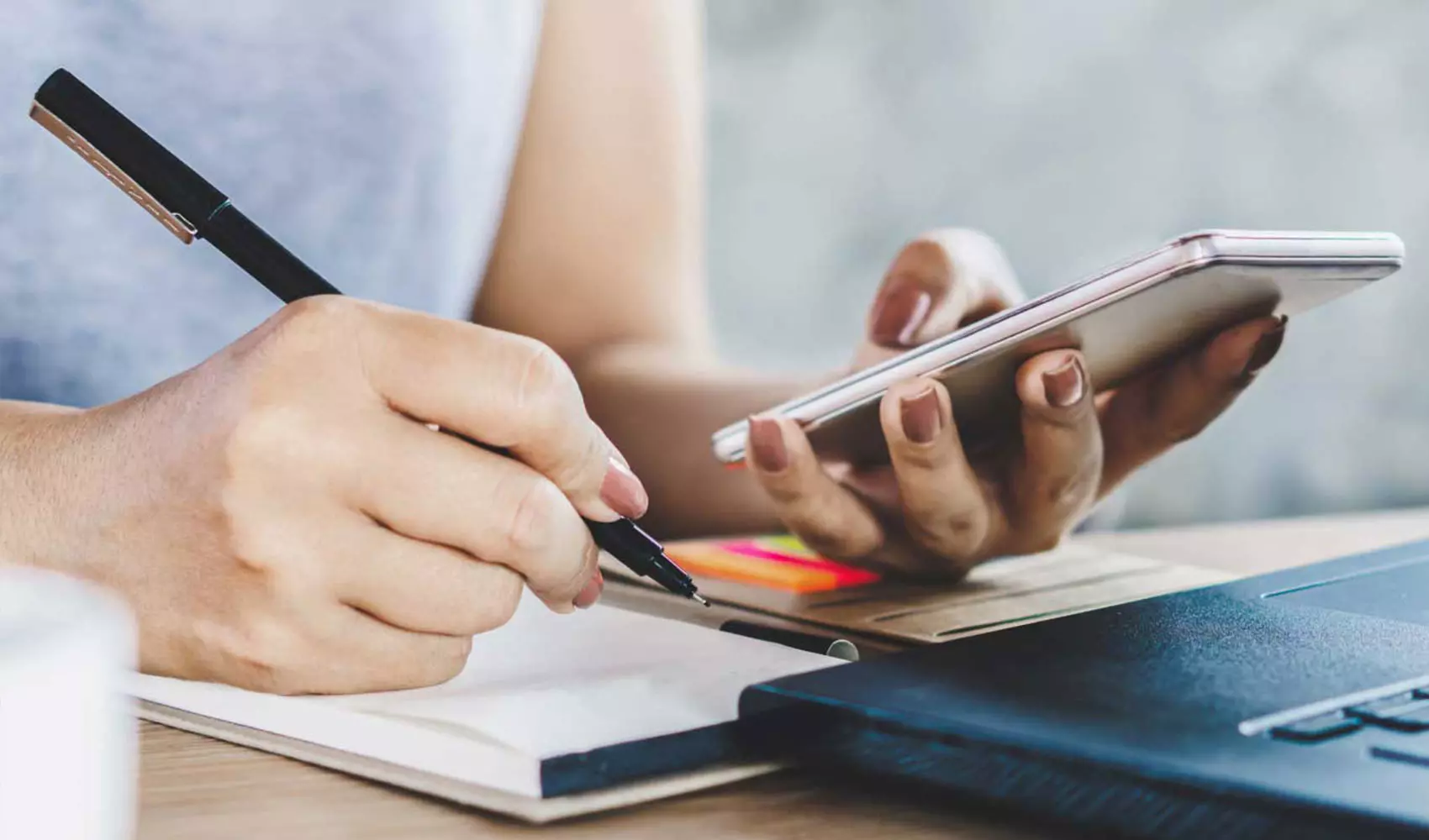 Woman writing while holding her phone