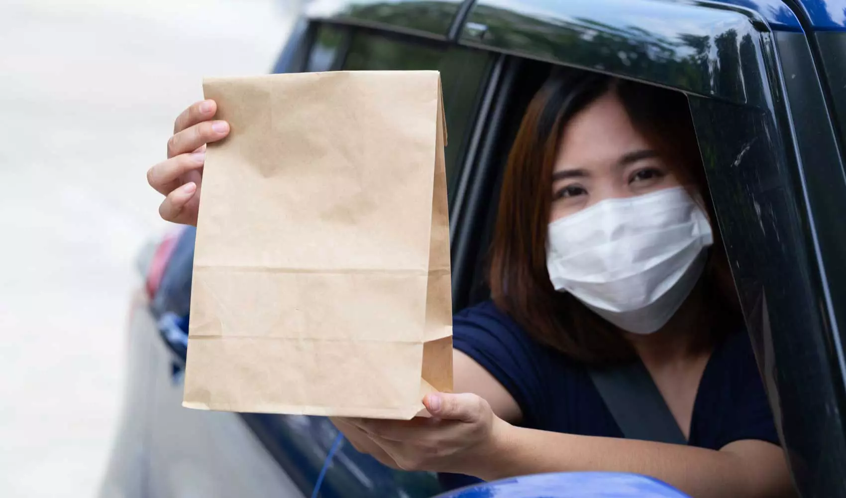 Asian woman wearing mask holding paper bag