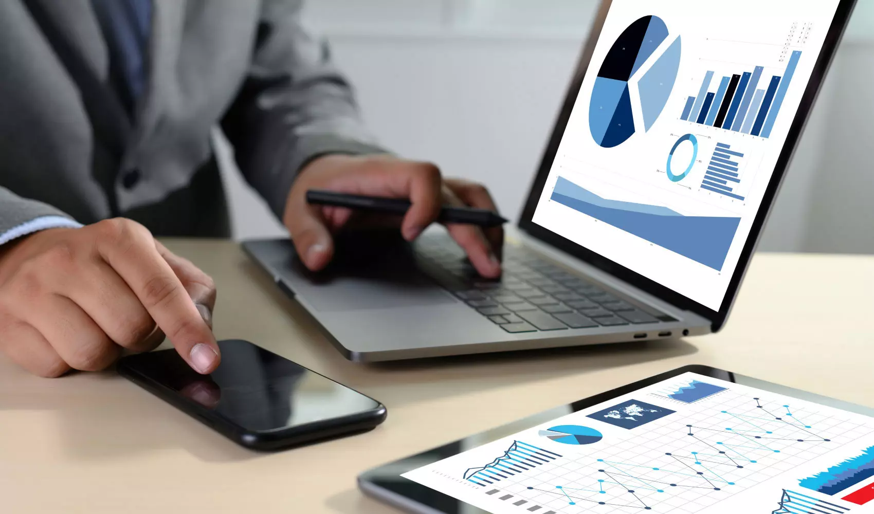 Man using phone and laptop showing different graphs 