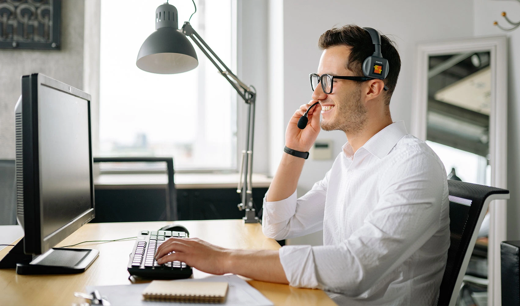 Smiling man wearing a headset looking at his computer screen
