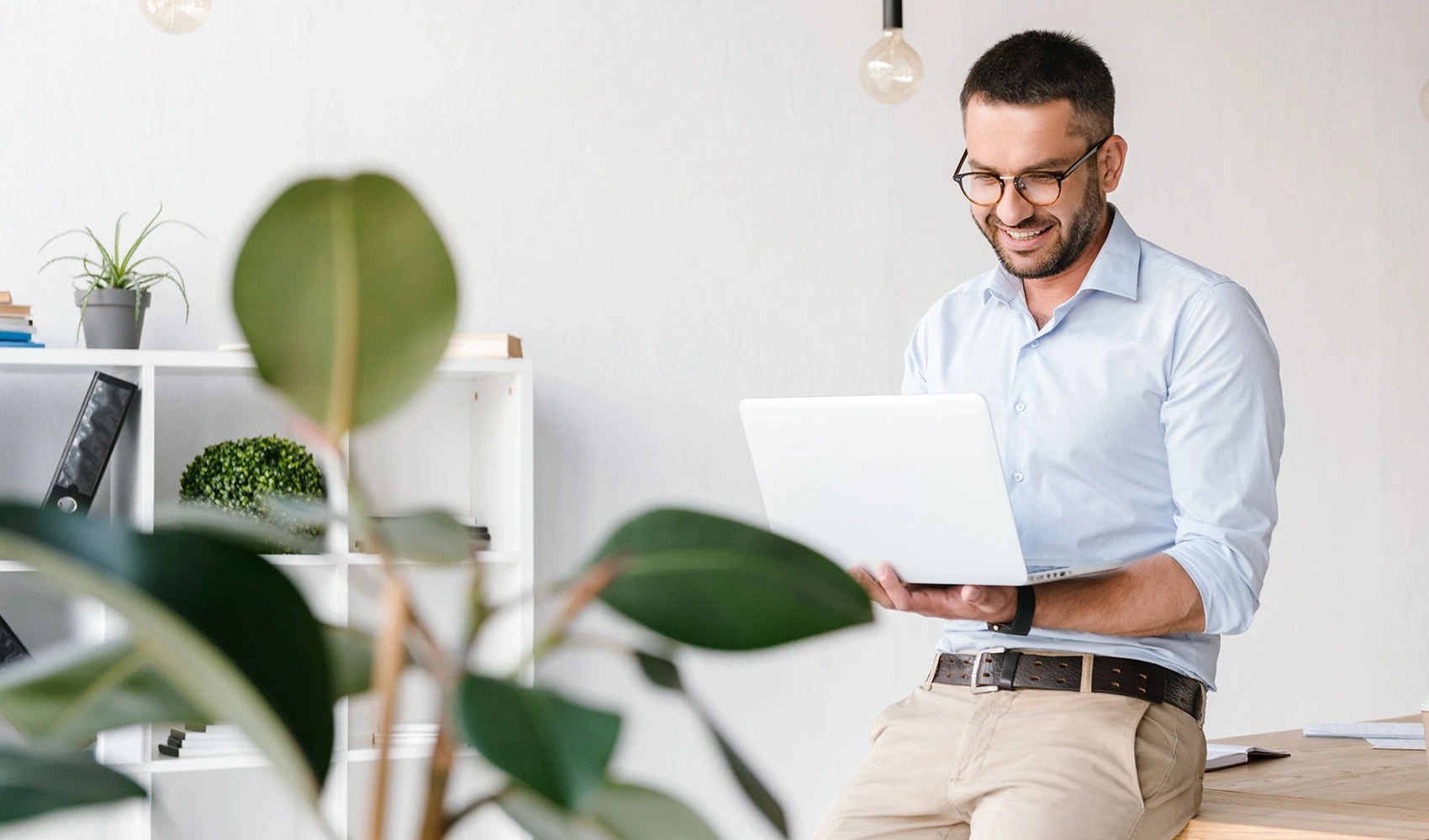 Smiling man sitting at the table while using laptop