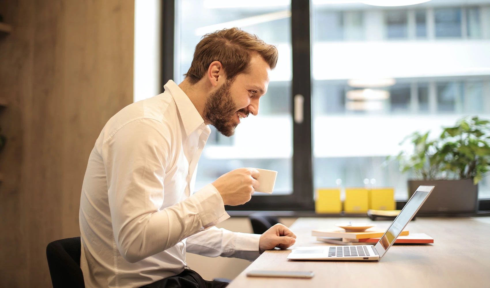 Man holding teacup infront of laptop