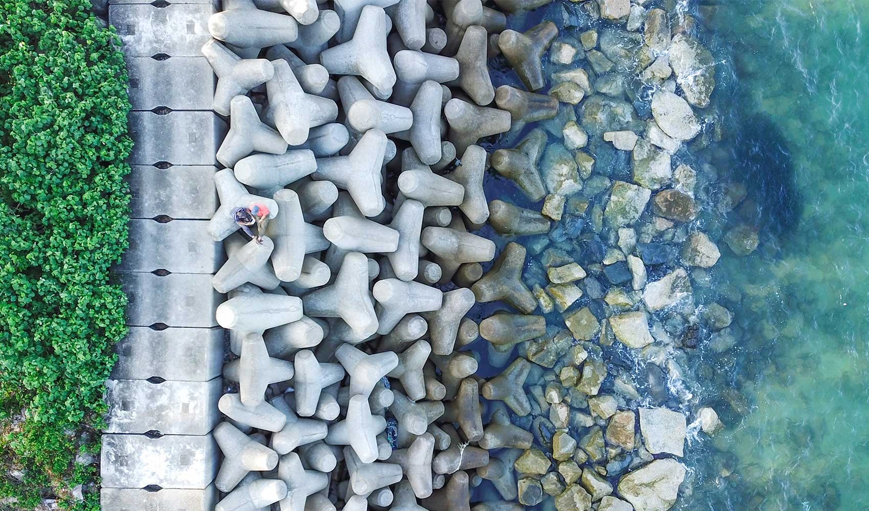 Aerial shot of azure sea near breakwater with concrete blocks