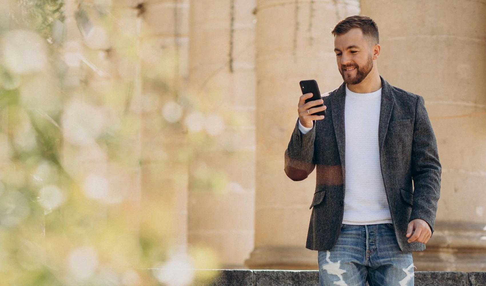 Handsome young business man using phone outside street