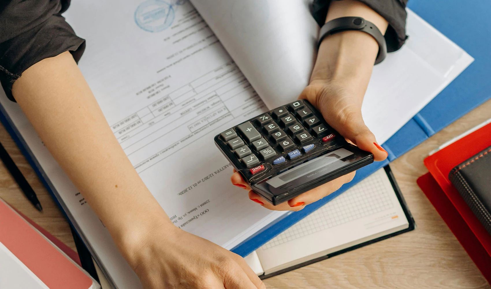 Person holding black calculator while using laptop