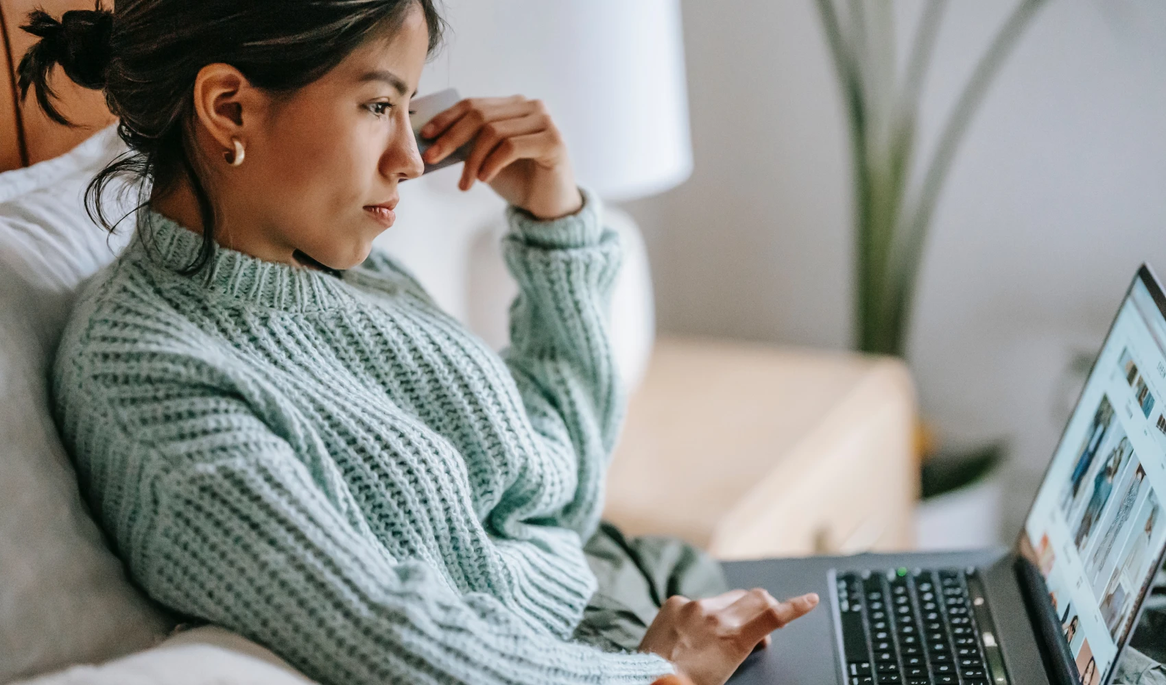 Woman sitting with a laptop holding a credit card