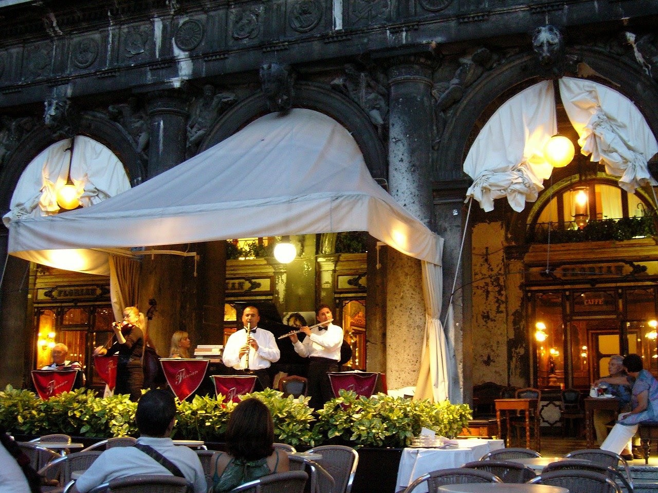 A group of classical musicians markets their group by performing live at a nice restaurant.