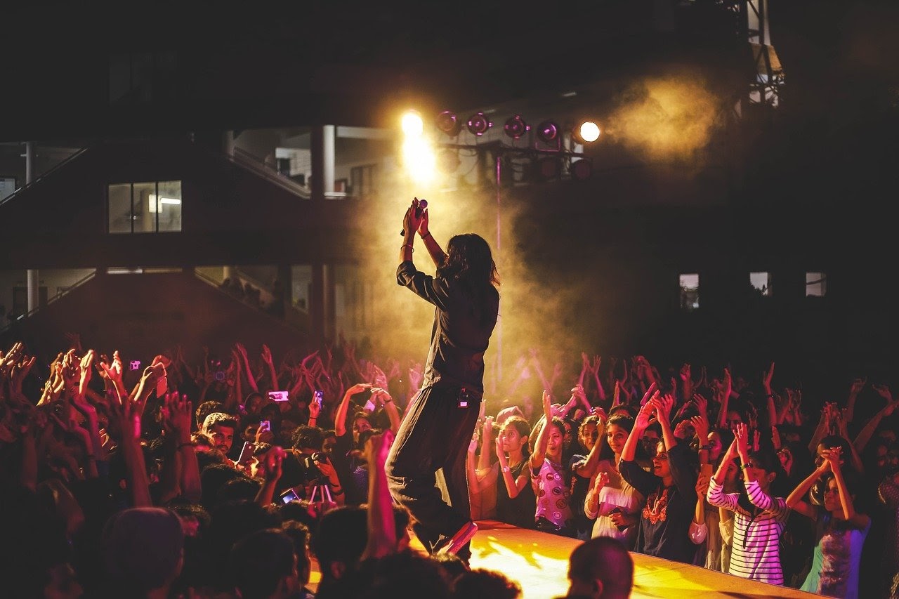 A charismatic singer engages his audience, getting them to clap along with him.
