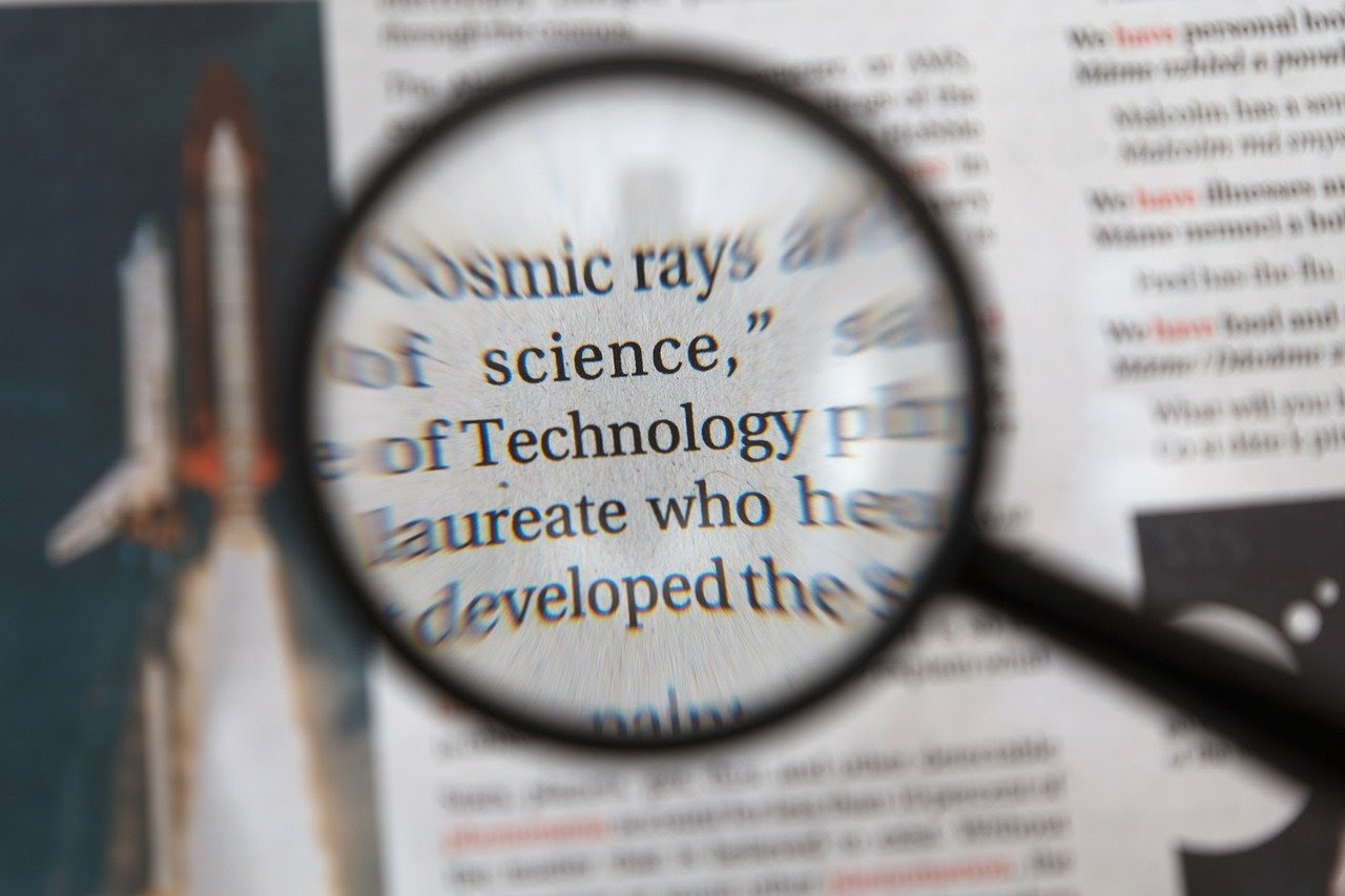 A person with a magnifying glass picks out keywords such as "science" and "technology" as keywords that their audience would be interested in