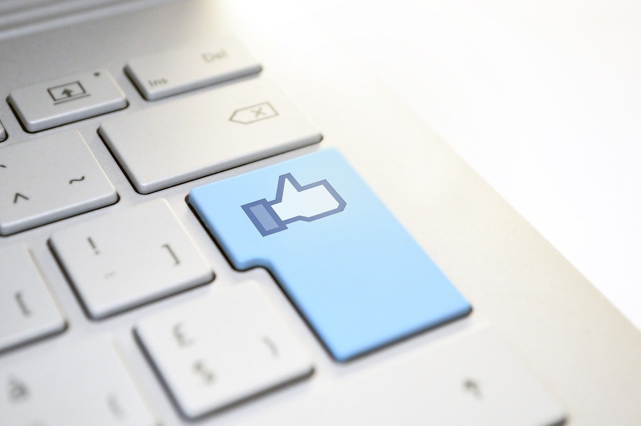 A like button is highlighted on a laptop keyboard