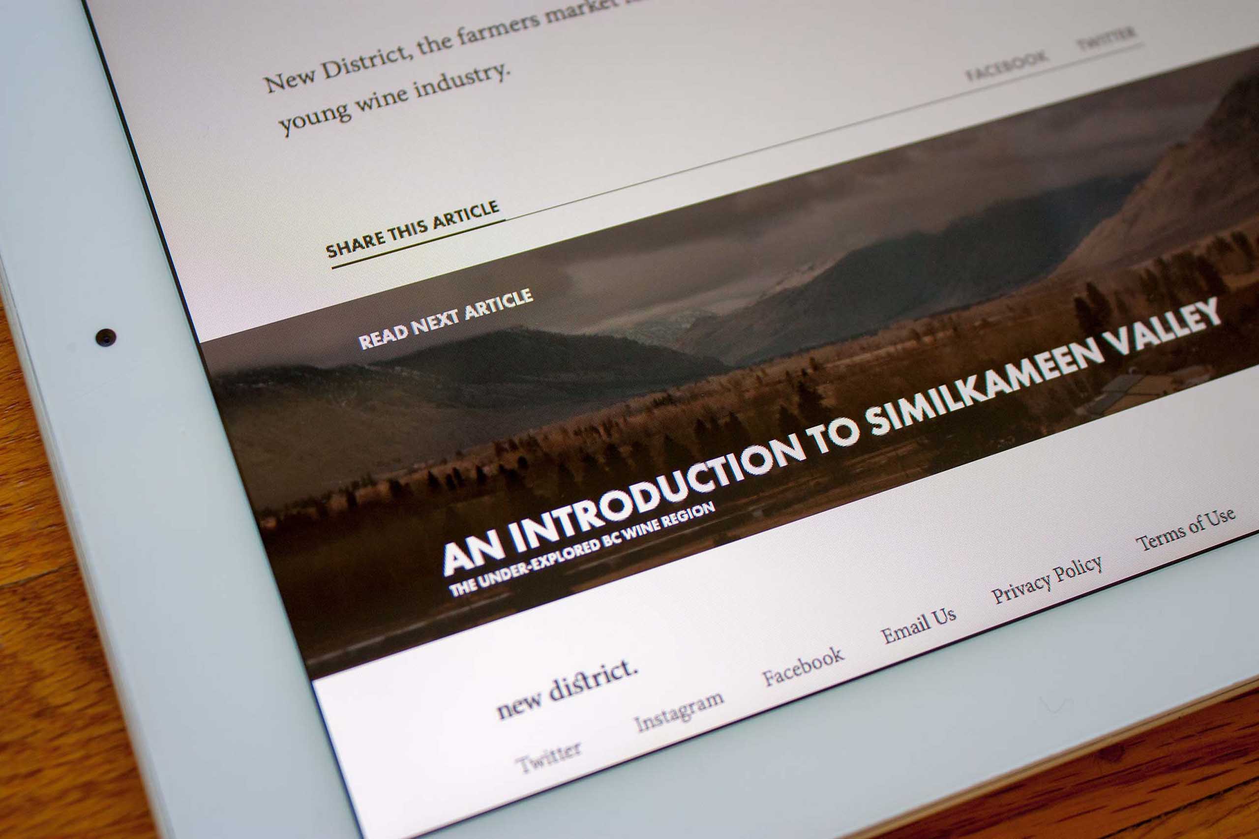 New District E-Commerce footer showing a prominent feature article with a background of Similkameen Valley in the interior BC — by Dima Yagnyuk.