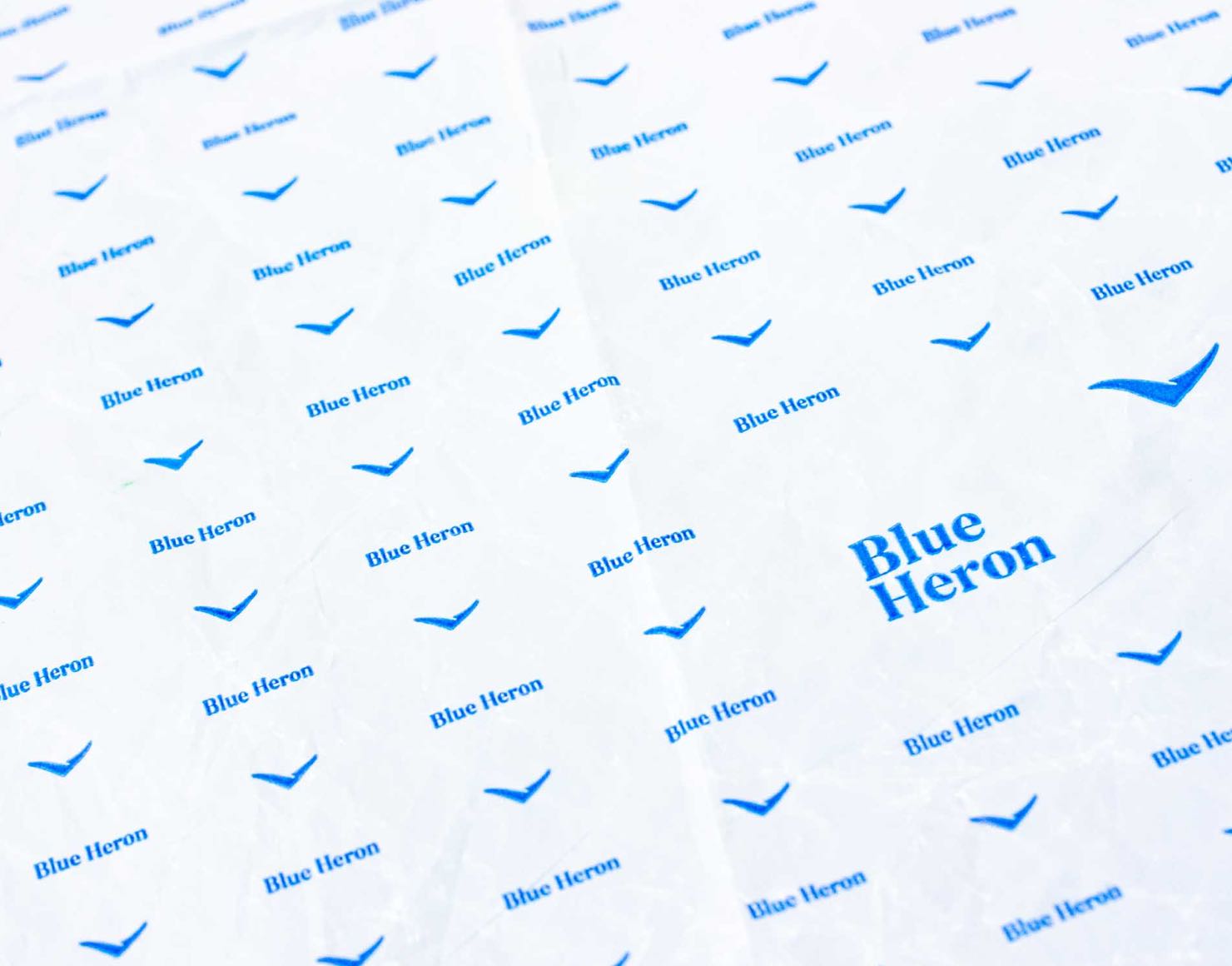 Blue Heron custom printed cheese paper with a repeating logo pattern — by Dima.