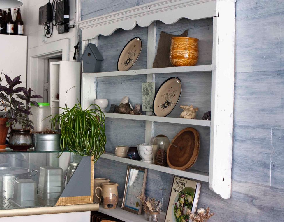 SOIl Restaurant interior with shelving holding vibrant ceramics and plants.