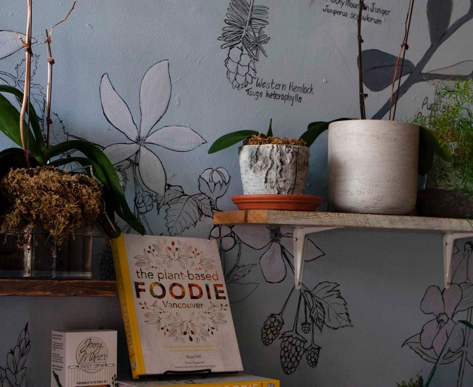 Blue Heron cheese shop interior walls featuring botanical illustrations, plants, ceramics, and plant related books for sale