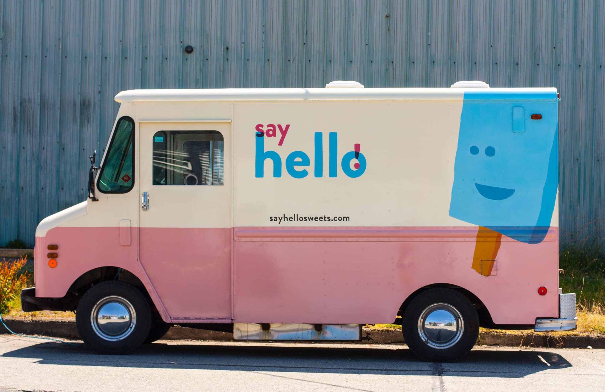Say Hello Ice Cream Truck side profile showing pink and white exterior with vibrant blue brandmark and ice cream bar character — by Dima.