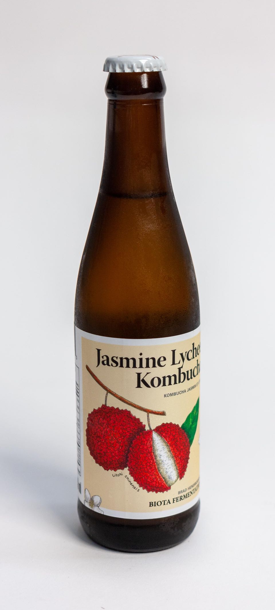 Biota Fermentation Jasmine Lychee Kombucha in 330ml bottle with vibrant red lychee illustration by Jessica Fraser — by Dima.