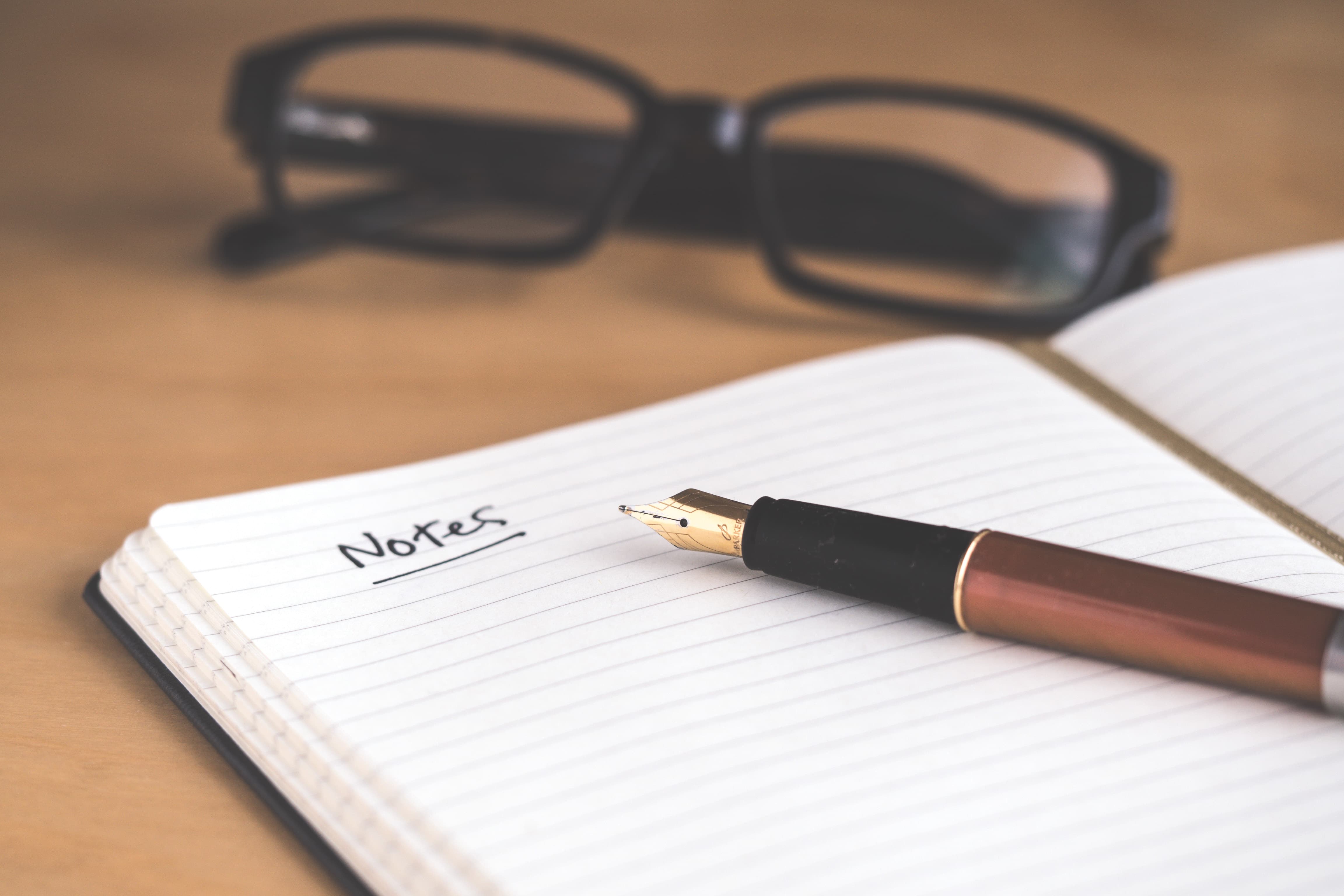 notepad on desk with the word Notes written on it with pen