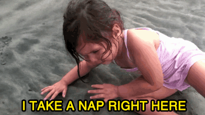 GIF of an exhausted little girl laying on the beach saying "I take a nap right here."