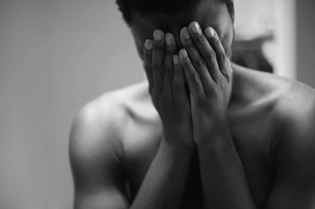 A sad man covering his face with his hand