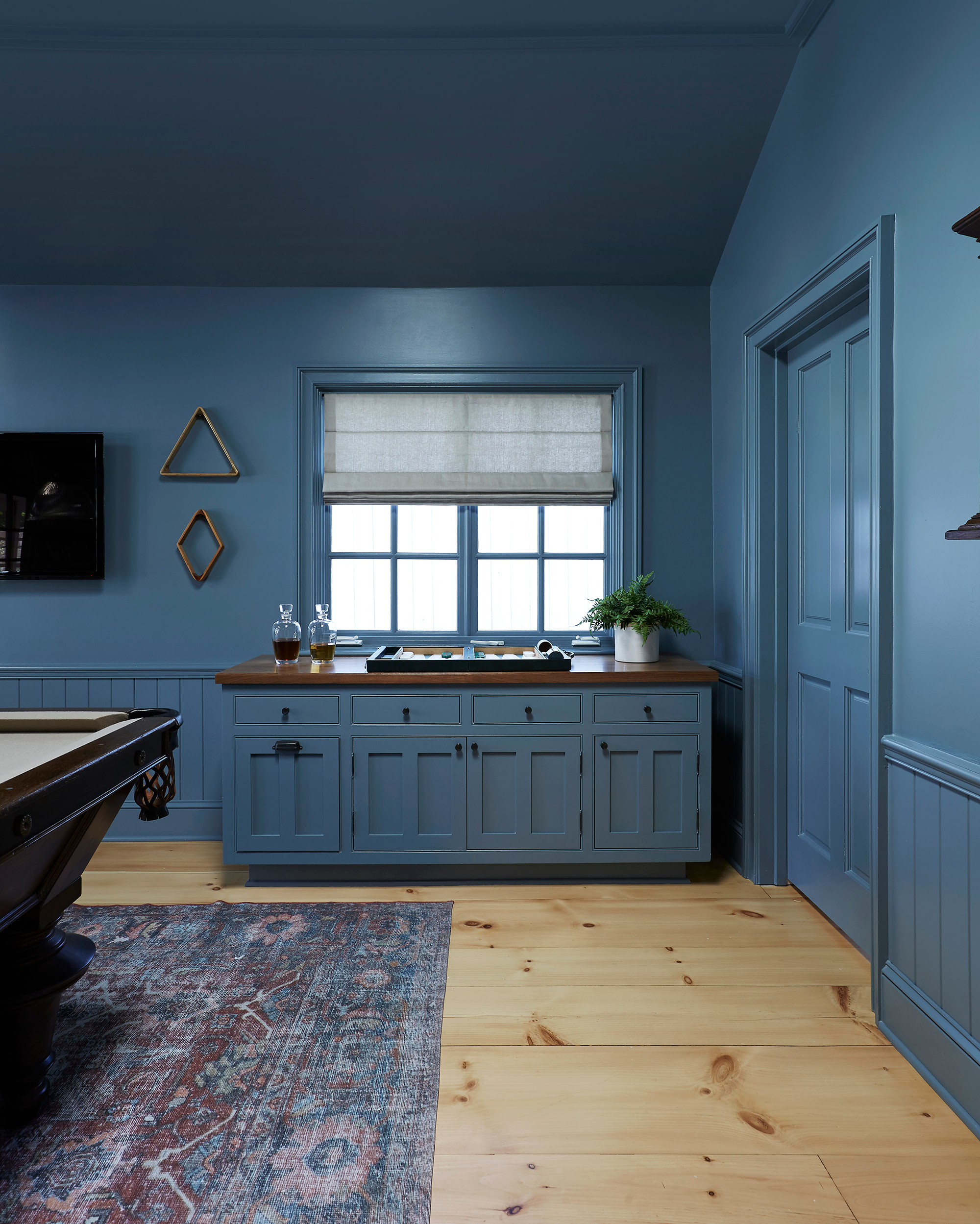 A Roman shade is mounted inside to accentuate the molding and craftmanship of this cool-blue rec room.
