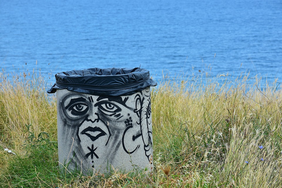 Trash can covered in graffiti of sad face